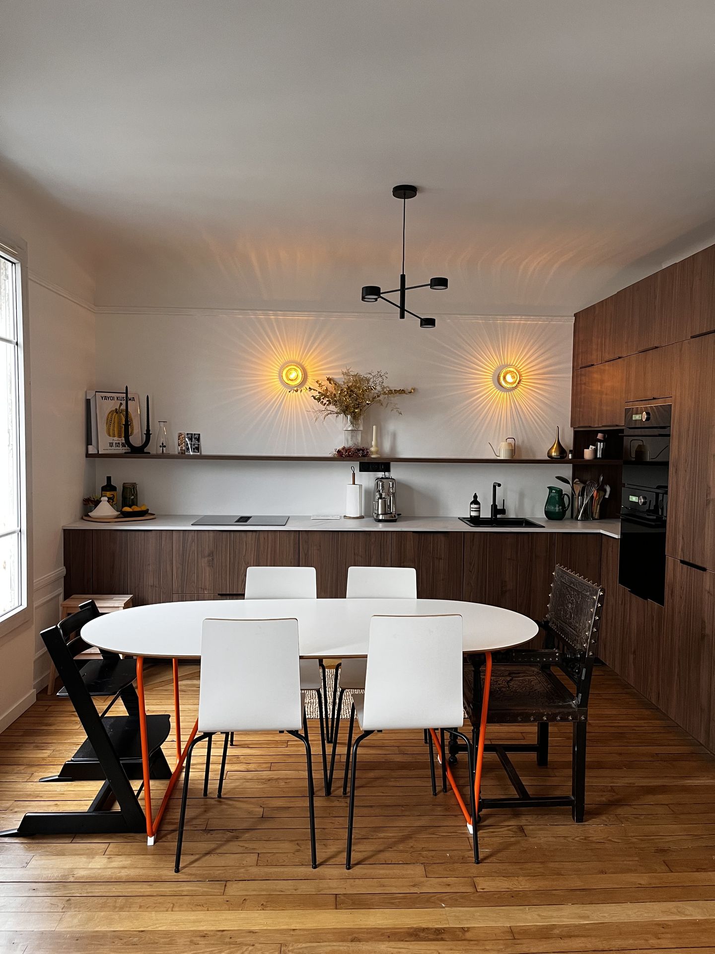Salle à manger design avec table ovale blanche et luminaires suspendus graphiques.