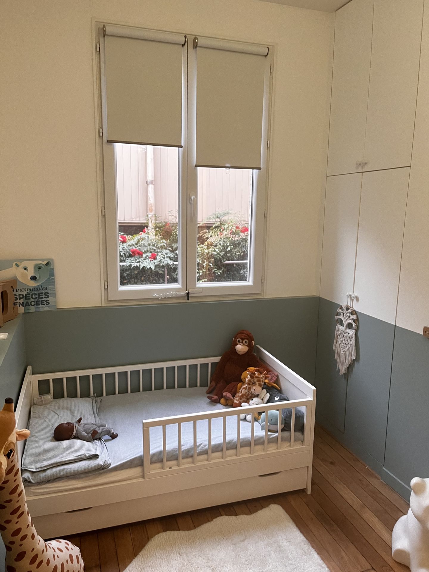 Chambre d'enfant douce avec lit à barreaux et décoration murale minimaliste et soignée.