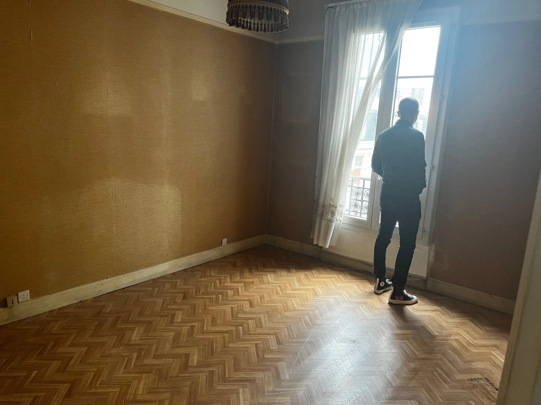 Vue d'un espace brut avec fenêtre haute, illustrant le travail de restructuration architecturale.